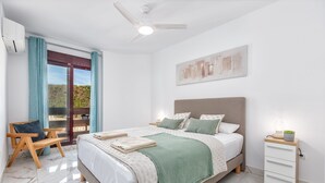 Ein Schlafzimmer mit Bett, Nachttisch, Sessel und Deckenventilator.