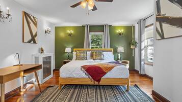 A bedroom with a wooden bed, a ceiling fan, a desk, and a radiator.