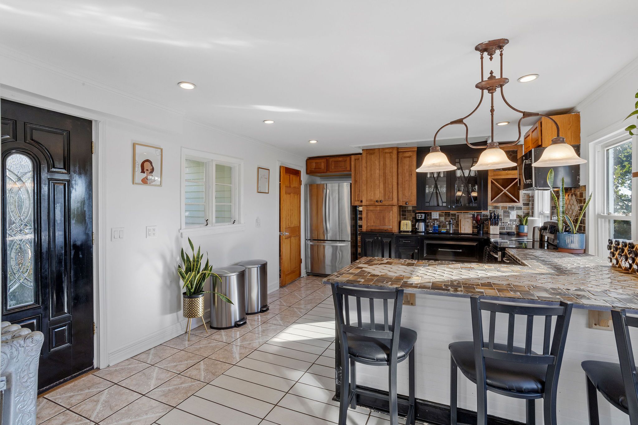A modern kitchen with a large island, wooden cabinets, and pendant lighting.