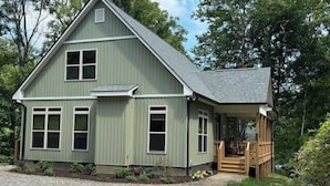 A two-story house with a porch, a gravel driveway, and a small garden.