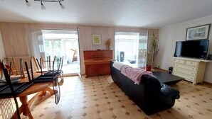 Een ruime woonkamer met een bank, een eettafel met stoelen, een televisie en een kast.
