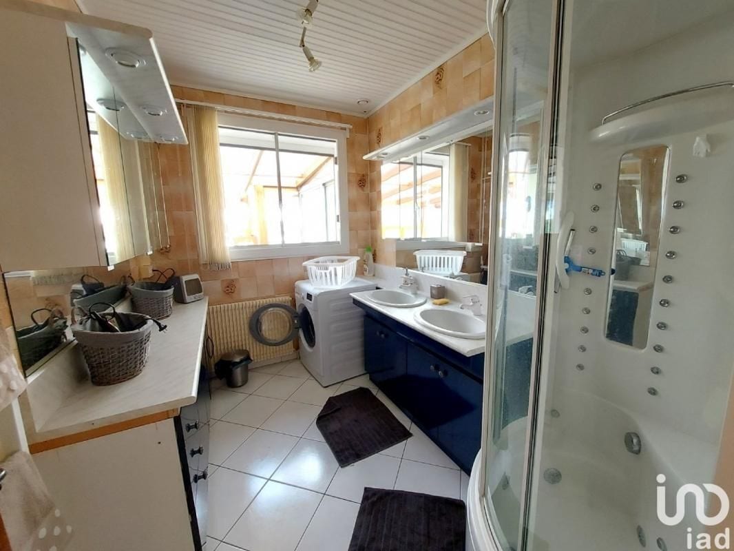 Un baño moderno con ducha, dos lavamanos, inodoro y lavadora.