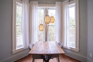 Een eethoek met een houten tafel, vier stoelen en een hoge vloerlamp met meerdere lampen.