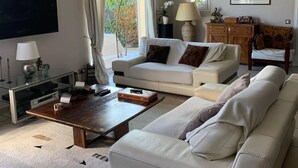 A modern living room with a white sofa, a coffee table, a TV, and a wooden cabinet. - BEAUTIFUL AC HOUSE WITH SWIMMING POOL AIX CENTER (Aix-en-Provence)