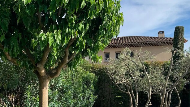 A swimming pool with a tiled deck, surrounded by greenery and a building in the background. - BEAUTIFUL AC HOUSE WITH SWIMMING POOL AIX CENTER (Aix-en-Provence)