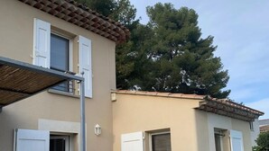 A two-story building with a tiled roof, white doors, and a small garden area with potted plants and a stone wall. - BEAUTIFUL AC HOUSE WITH SWIMMING POOL AIX CENTER (Aix-en-Provence)
