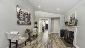A hallway with a dining area featuring a table and chairs, a fireplace, and a large black and white cityscape painting on the wall. - Walk across the street to Disneyland parking. Fireworks show from front porch! (Anaheim)