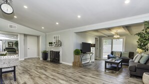 A spacious living room with hardwood flooring, a fireplace, a television, and a sofa. - Walk across the street to Disneyland parking. Fireworks show from front porch! (Anaheim)