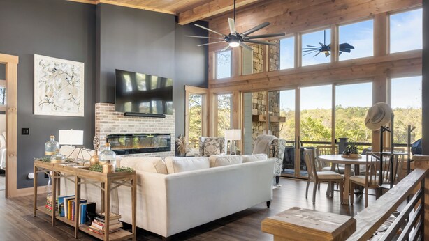 A modern living room with a fireplace, a large TV, and a dining area with outdoor views.