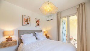 Ein Hotelzimmer mit einem großen Bett, zwei Nachttischlampen, einer Deckenleuchte und Blick auf den Außenbalkon.