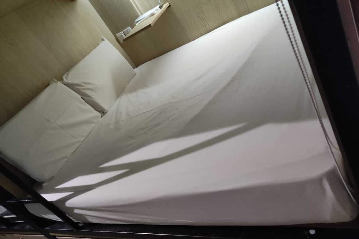 A single bed with white bedding in a room with a wooden headboard and a small bedside table.