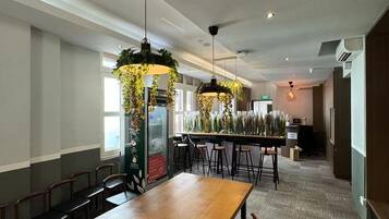 A conference room with a long wooden table, multiple chairs, hanging plants, and pendant lights.