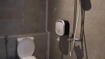 Een moderne badkamer met toilet, handdroger en douche.