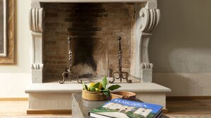 Una chimenea con revestimiento de ladrillo, un elegante repisa decorativa y una pequeña mesa con un libro y un cuenco de flores.