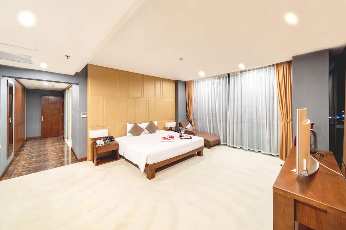 Una habitación de hotel con una cama grande, mesitas de noche, un escritorio y un televisor.