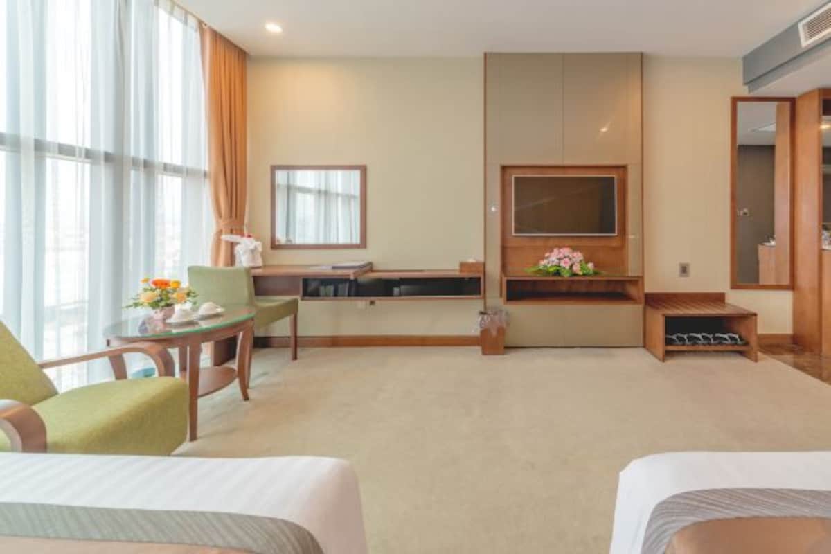 A hotel room with a bed, a desk, a chair, a TV, and a window with curtains.
