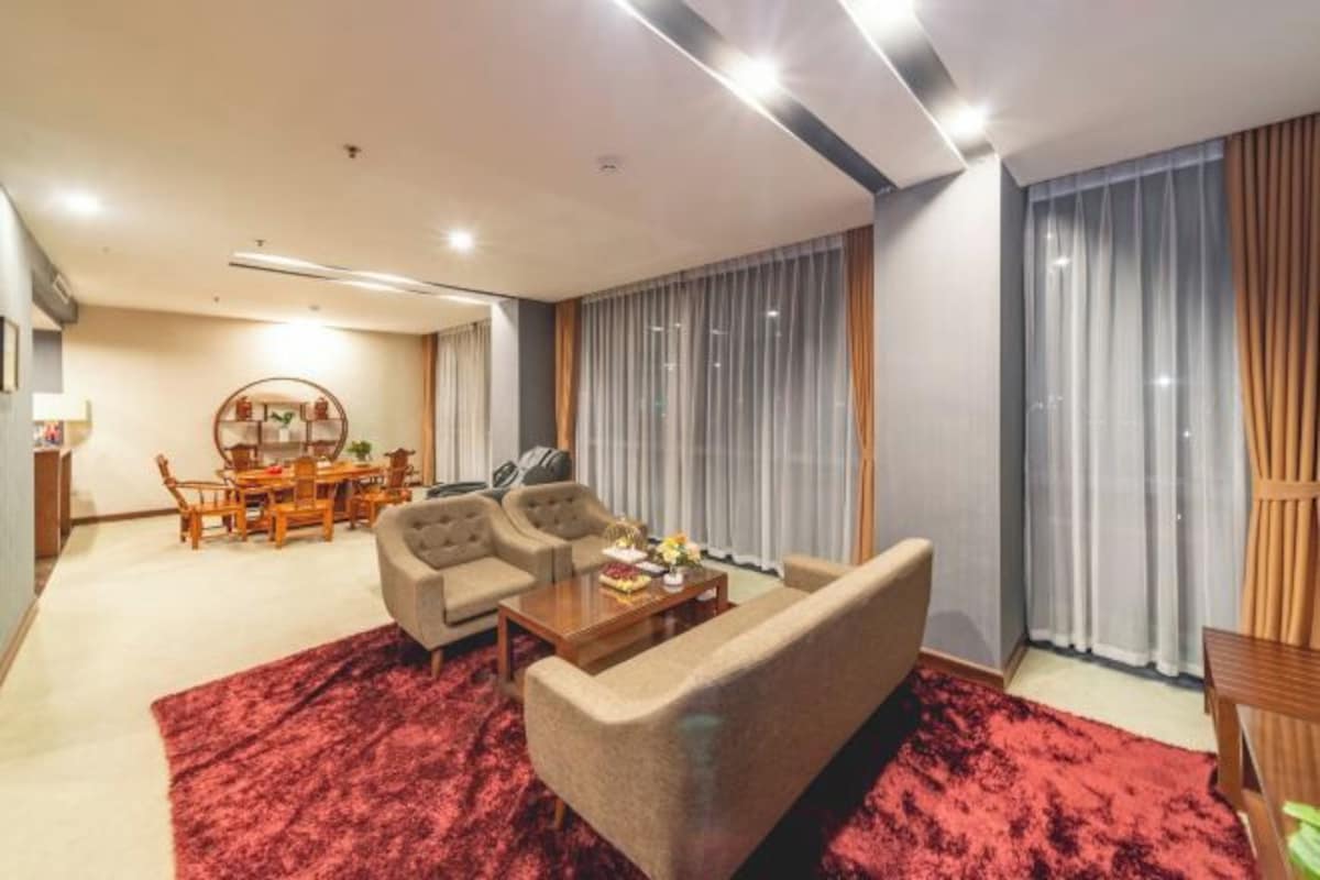 A modern living room with a red carpet, two sofas, a coffee table, and a dining area with a wooden table and chairs.