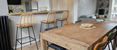 A modern kitchen with a wooden table and chairs, a built-in oven, and a dining area with a view of the living room.