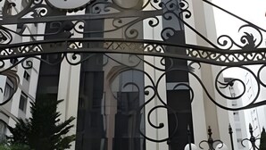 Um edifício moderno com um grande letreiro em formato de 'P', janelas amplas e detalhes em ferro forjado.