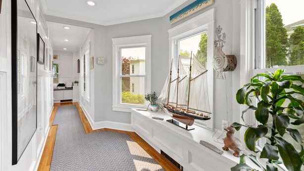 A hallway with a wooden floor, a built-in bench with a ship model, and a potted plant. - Mystic on Broadway! Downtown. Your Ultimate Mystic Getaway. Just Steps to it All (Stonington)