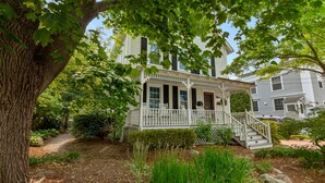 A two-story house with a porch and a staircase leading to the entrance. - Mystic on Broadway! Downtown. Your Ultimate Mystic Getaway. Just Steps to it All (Stonington)