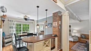 A modern kitchen with a central island, pendant lighting, and a brick accent wall. - Mystic on Broadway! Downtown. Your Ultimate Mystic Getaway. Just Steps to it All (Stonington)