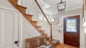 A staircase with wooden railings and a bench with patterned cushions. - Mystic on Broadway! Downtown. Your Ultimate Mystic Getaway. Just Steps to it All (Stonington)