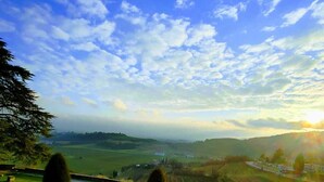 A landscaped garden with a central circular feature, pathways, and a view of distant hills under a partly cloudy sky. - Il Castello (Barbarano Vicentino)