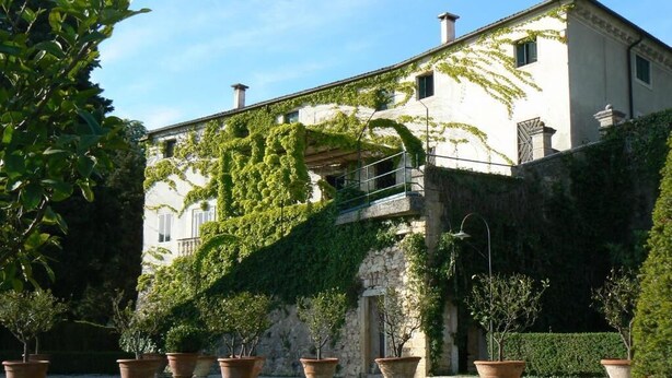 A building with a stone facade, large potted plants in the foreground, and a clear sky. - Il Castello (Barbarano Vicentino)