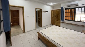 Ein Schlafzimmer mit einem Bett, einem Kleiderschrank, einer Tür und einer Klimaanlage.