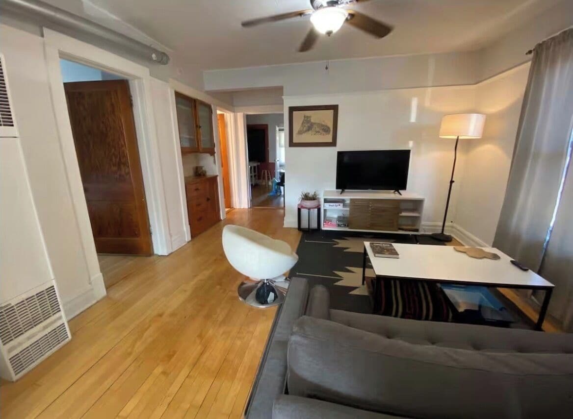 A living room with a sofa, a TV, a lamp, and a ceiling fan.