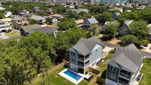A residential area with two two-story houses featuring attached garages, a swimming pool, and a view of the ocean.