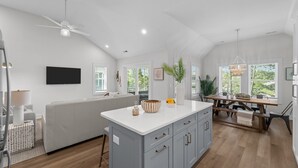 A modern kitchen with a central island, a dining area with a wooden table, and a seating area with a sofa.