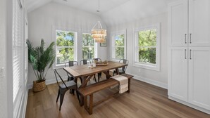 A dining area with a wooden table, benches, and a hanging light fixture.