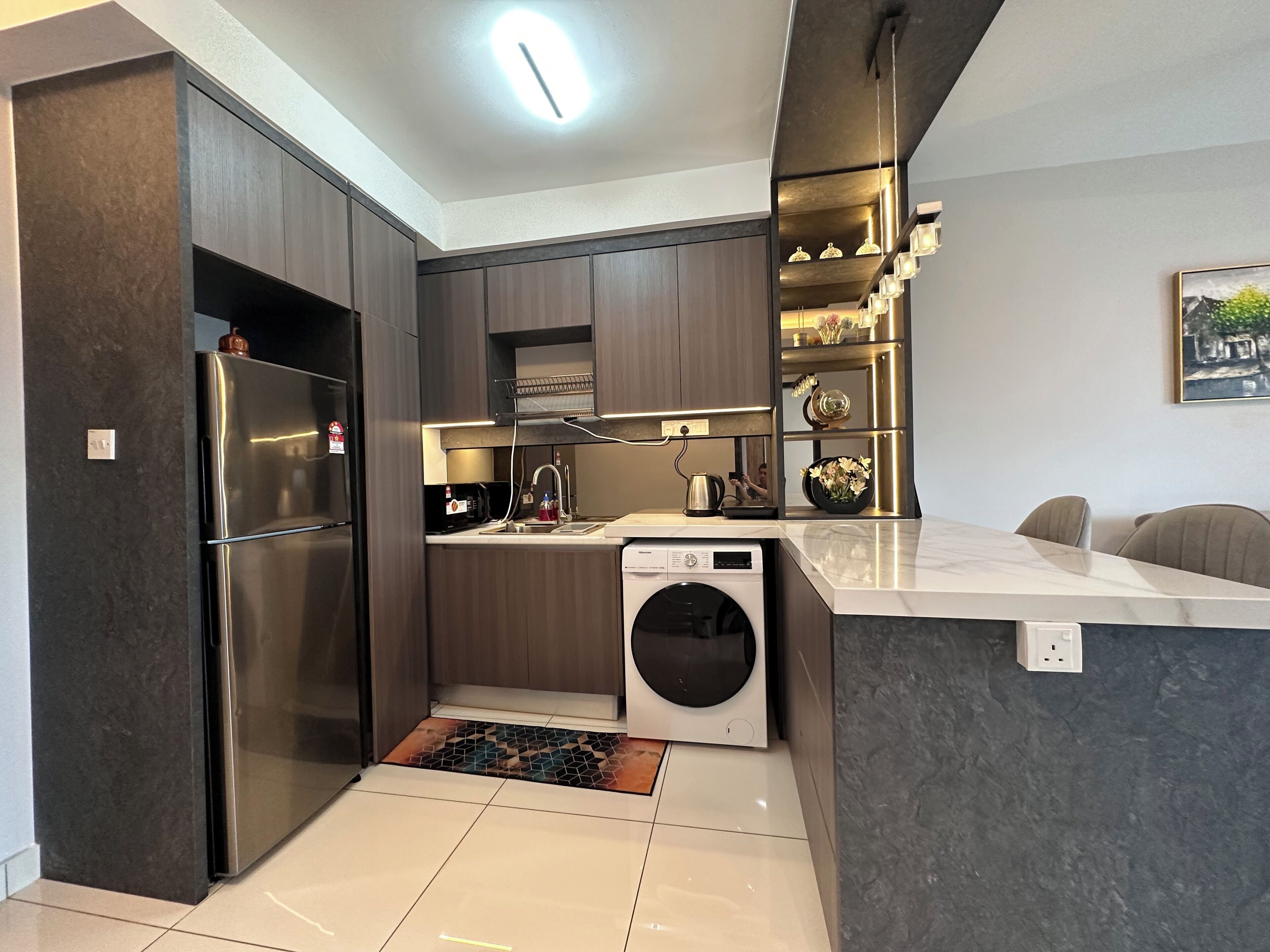 Une cuisine moderne avec des meubles en bois foncé, des appareils électroménagers en acier inoxydable et un lave-linge encastré.
