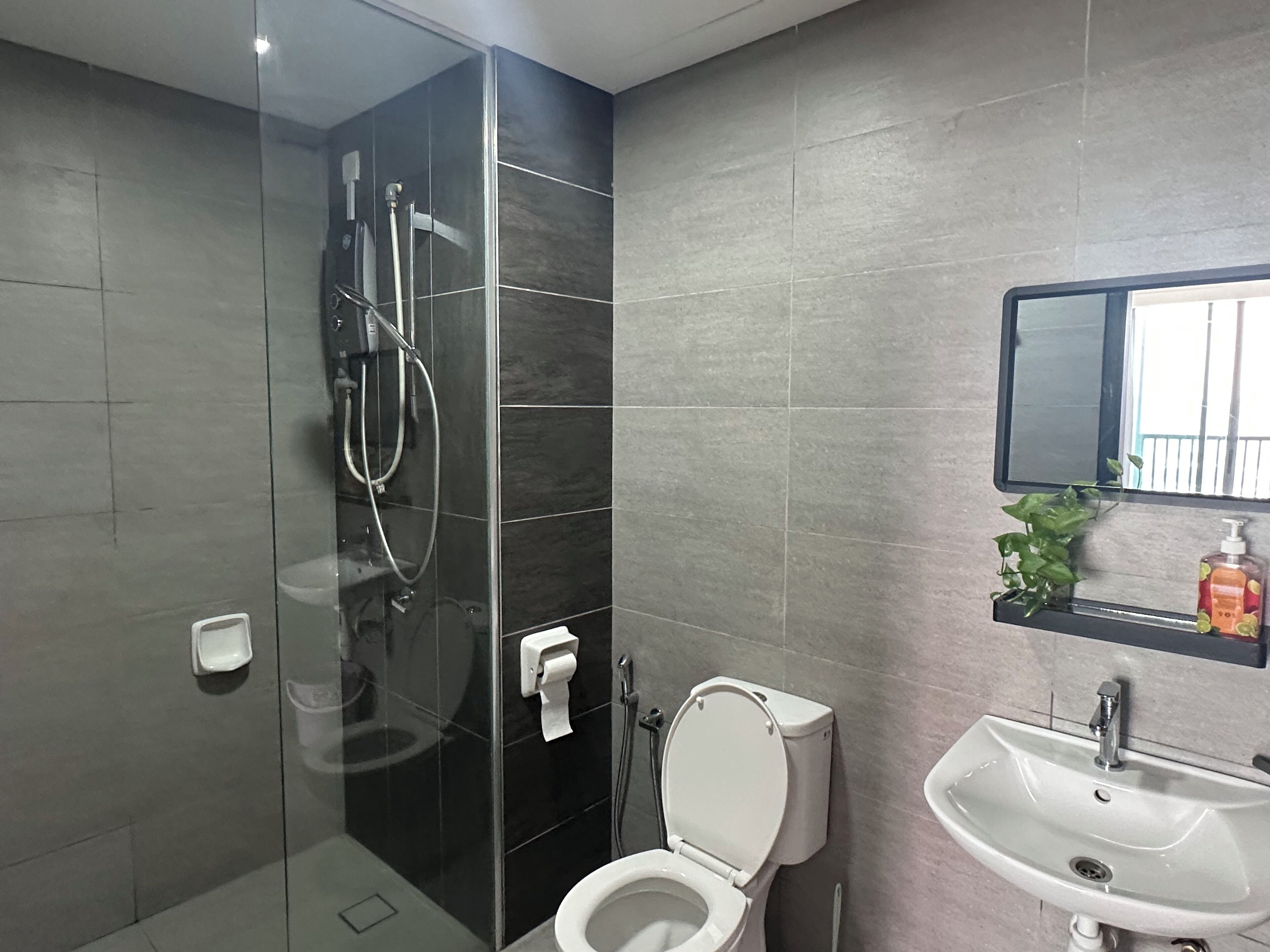 Une salle de bain moderne avec une douche à parois de verre, des toilettes et un lavabo surmonté d’un miroir.