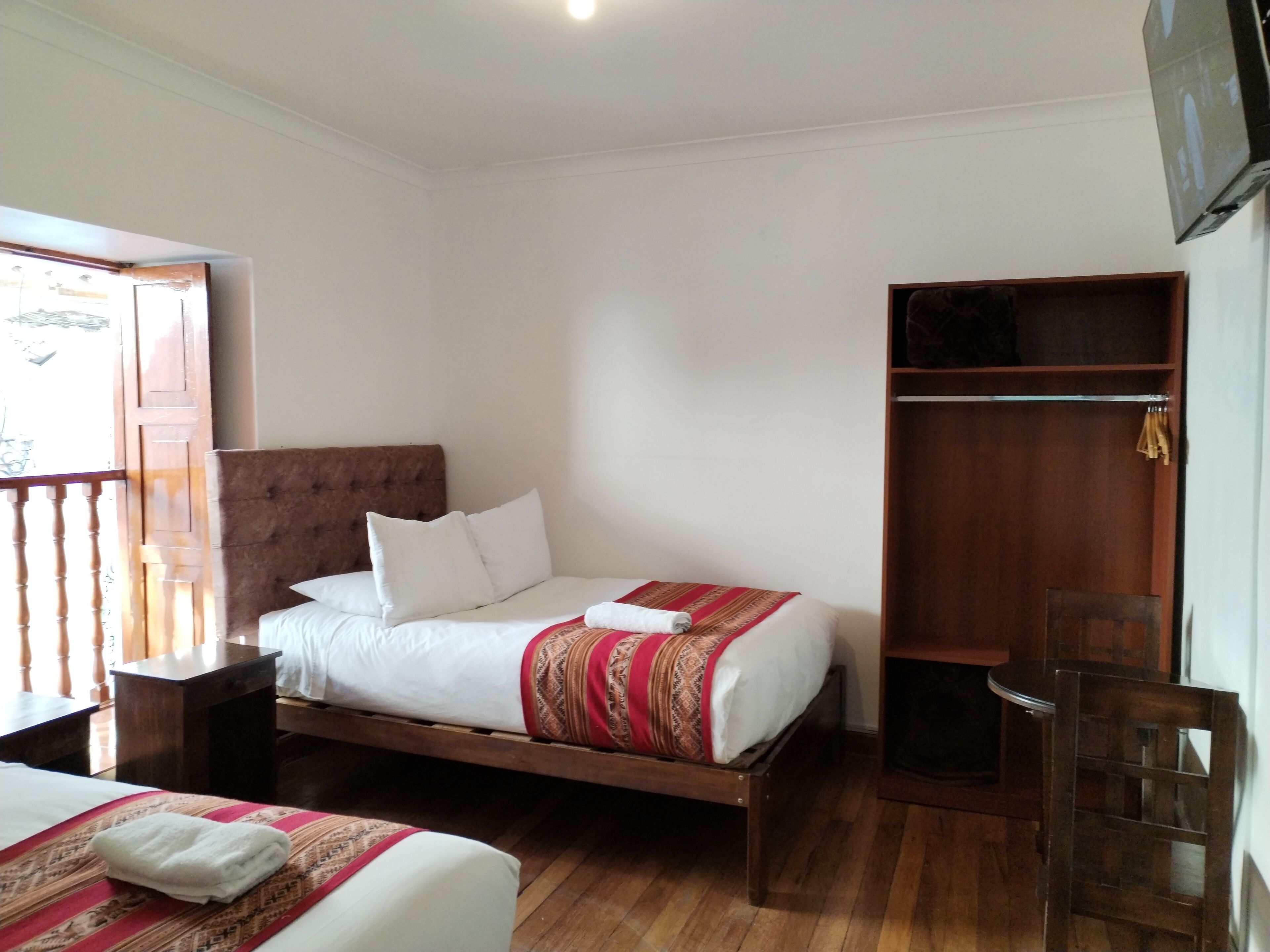 A single bed with a wooden headboard, a wooden wardrobe, and a wooden chair.