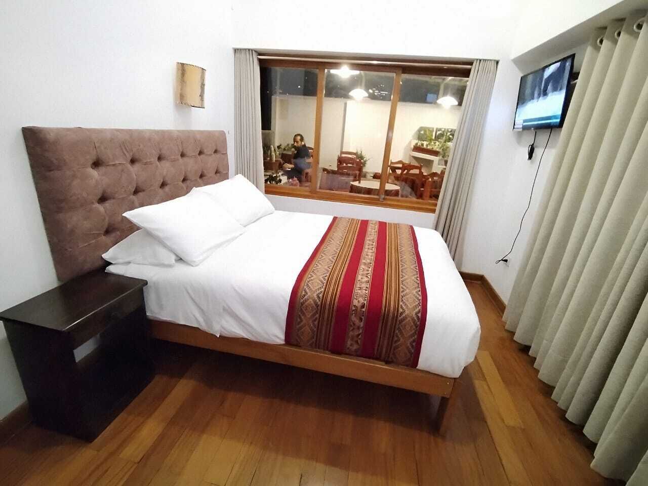 A bedroom with a bed, a nightstand, a television, and a view of the outdoor area.