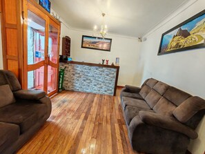 A hotel lobby with wooden flooring, a reception desk, and two sofas. - Paqarina san Blas (Cusco)