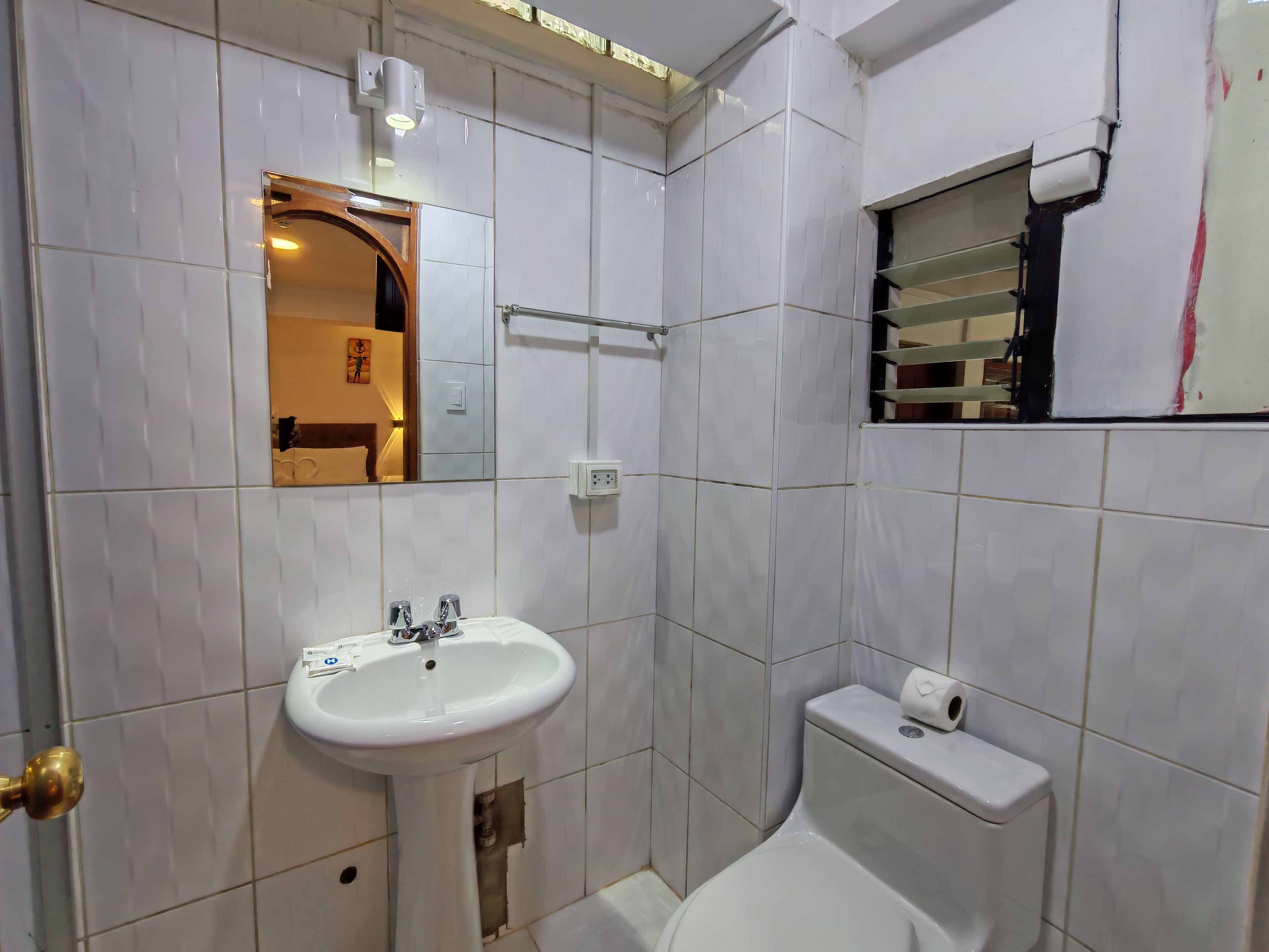 A bathroom with a white sink, a toilet, a mirror, and a towel rack.