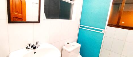 A bathroom with a sink, toilet, and a blue shower enclosure.