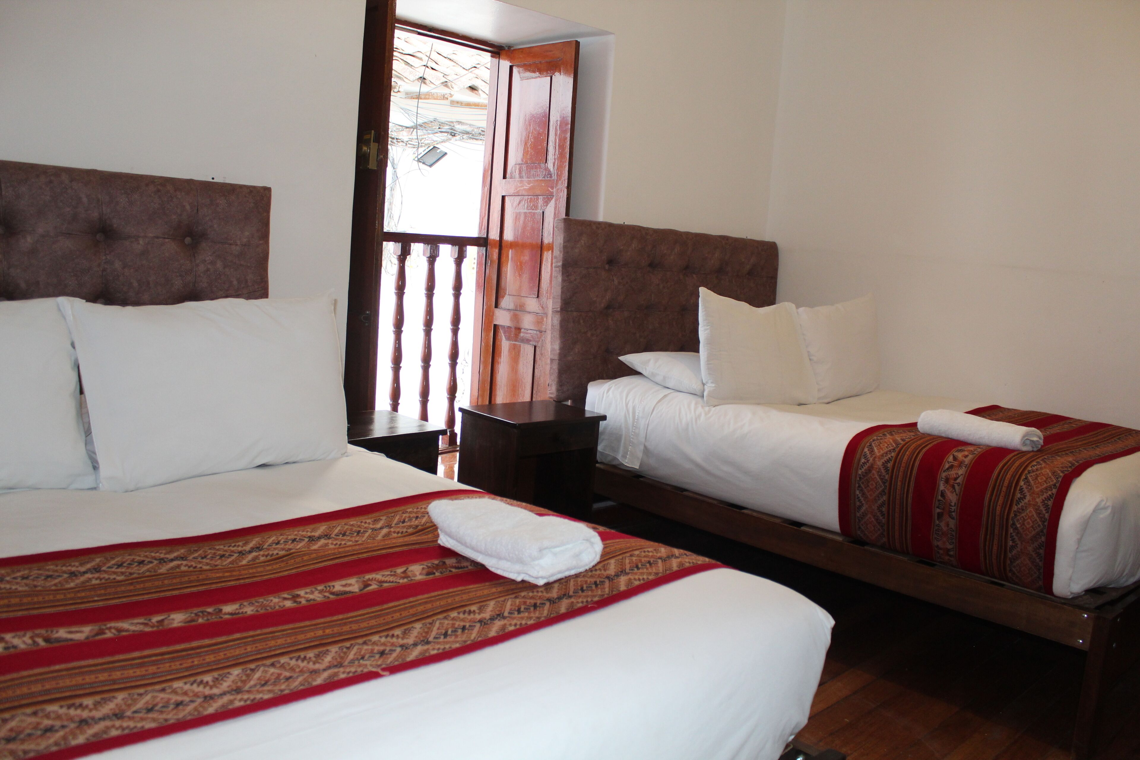 A hotel room with two beds, a wooden headboard, and a nightstand.