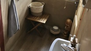 A compact bathroom with a window, a sink, a mirror, a towel rack, and a small shelf with a vase. - Kouzelná maringotka (Chribska)