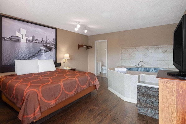 A hotel room with a bed, a bathroom with a bathtub, and a large window with a cityscape view. - Super 8 by Wyndham Youngstown/girard (Girard)
