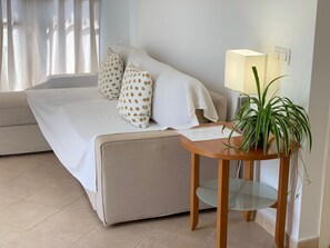 Ein ordentlich eingerichtetes Schlafzimmer mit einem Bett, Kissen, einem Nachttisch mit Lampe und einer Topfpflanze.