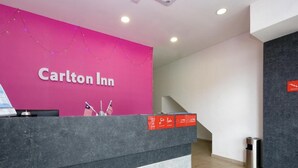 A Carlton Inn reception desk with a pink wall, a digital screen, and a trash can. - OYO 89492 Carlton Inn Bukit Ubi (Kuantan)