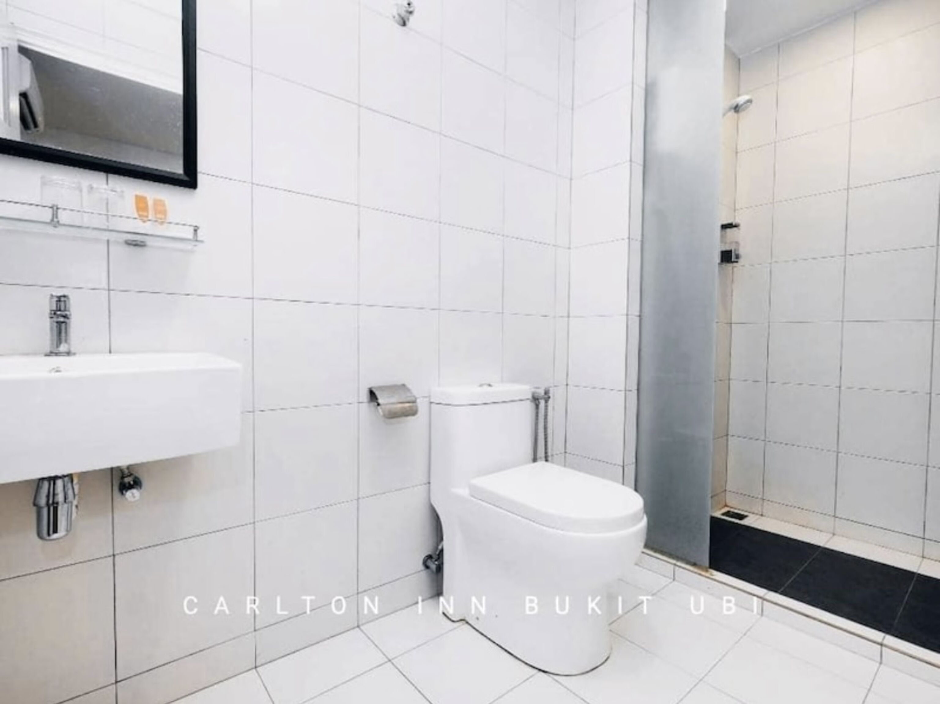 Une salle de bain moderne avec un lavabo blanc, des toilettes et une douche à parois de verre.
