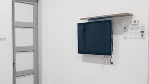 A room with a wall-mounted flat-screen TV, a door, and a power outlet. - OYO 89492 Carlton Inn Bukit Ubi (Kuantan)