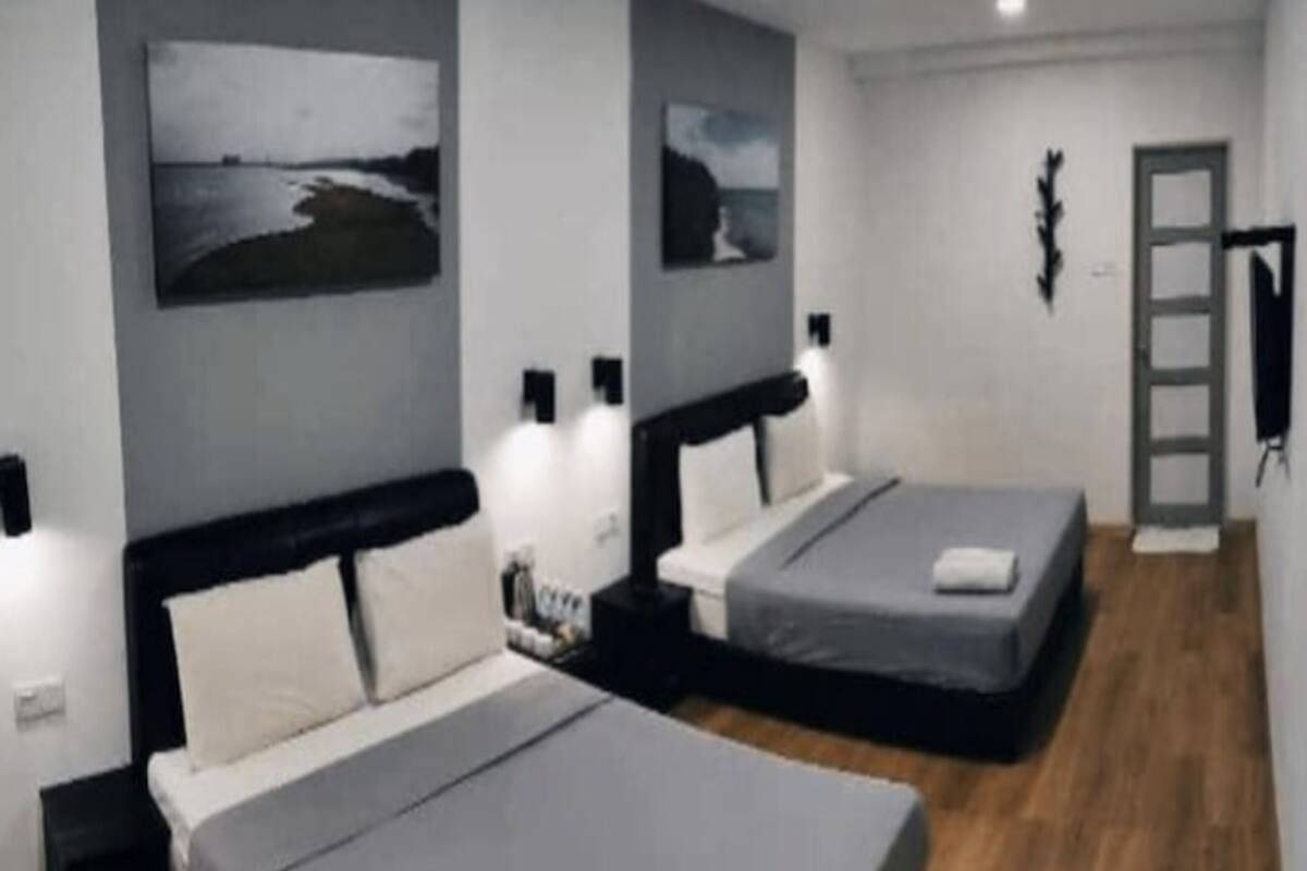 A hotel room with two beds, a wooden floor, and artwork on the walls.
