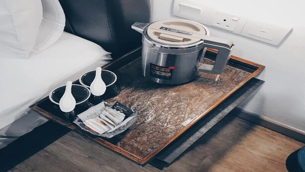 A small kitchenette with a coffee maker, a kettle, and a tray with glasses and coffee packets. - OYO 89492 Carlton Inn Bukit Ubi (Kuantan)